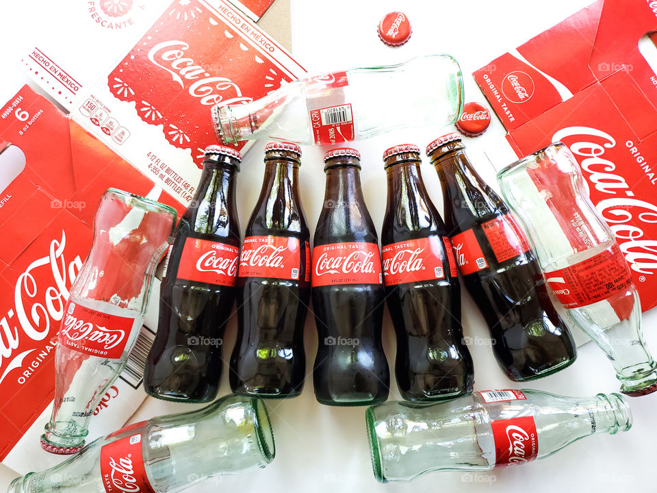 Coca-Cola bottles both new and consumed along with the original cardboard packaging.