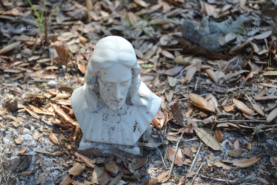 Small bust of Jesus in mulch at cemetery 