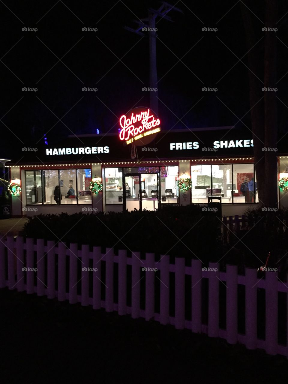 Johnny Rocket's diner restaurant with neon lights at night with a fence in front.  