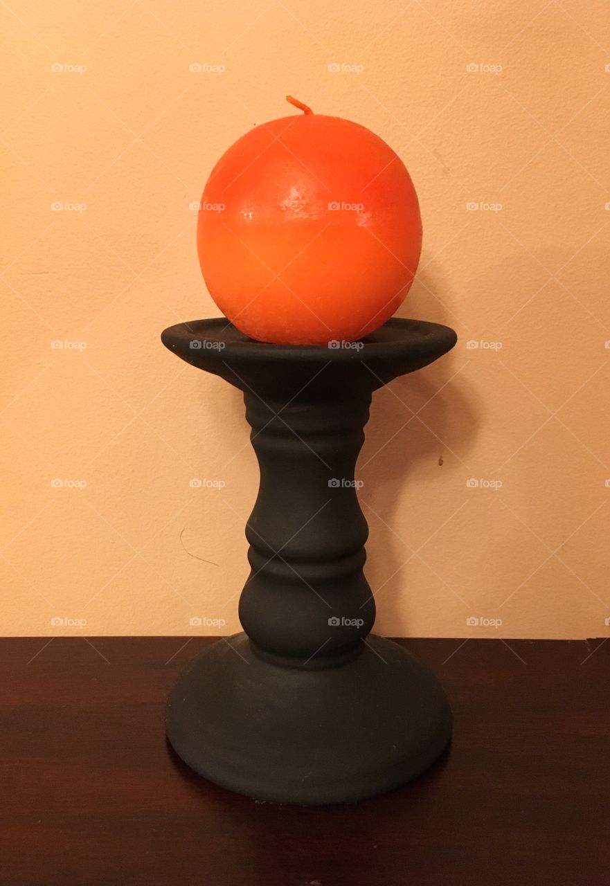 Round orange candle on black candlestick for Halloween