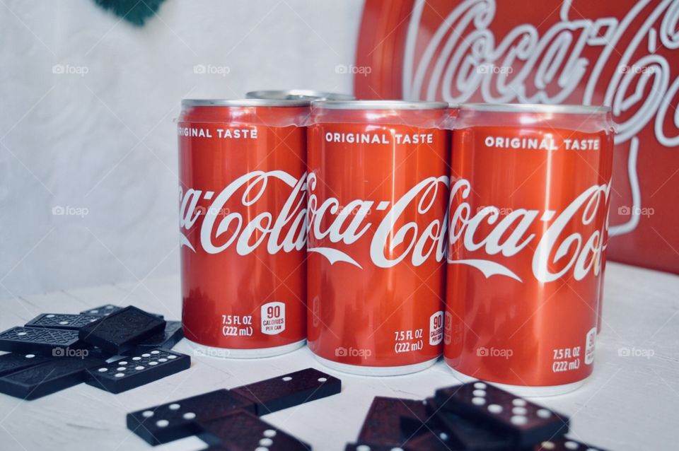 A six pack of Coca Cola cans with dominos 