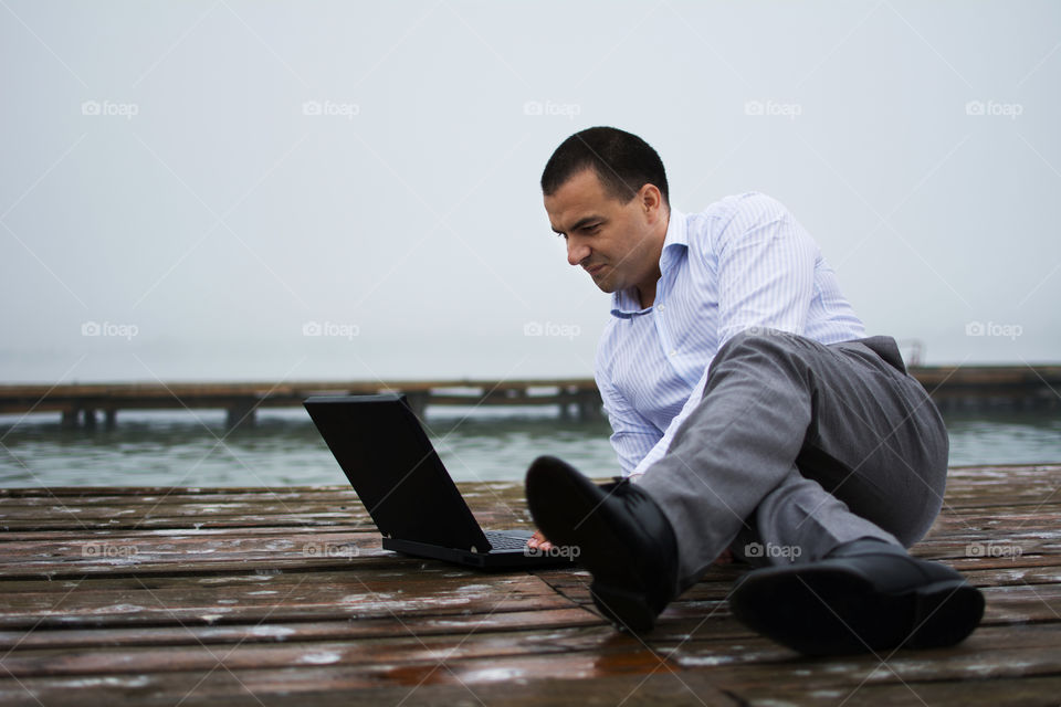 Man on lake dock with laptop