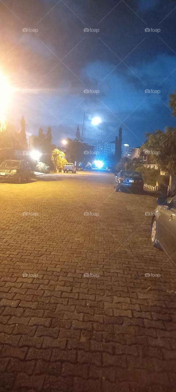 Moon and street lights creating an illusion of many moons with one on the ground