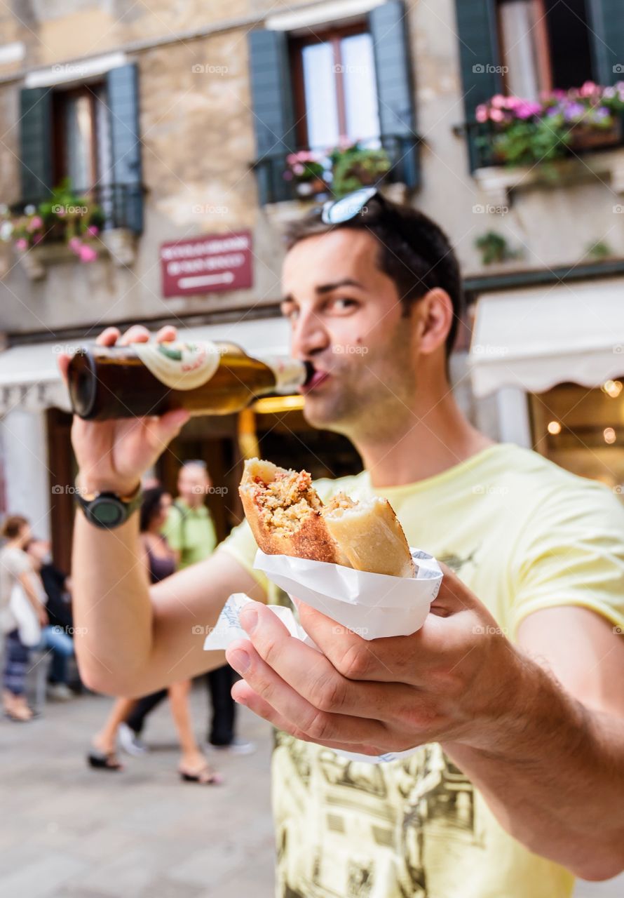 Man showing fast food while drinking beer