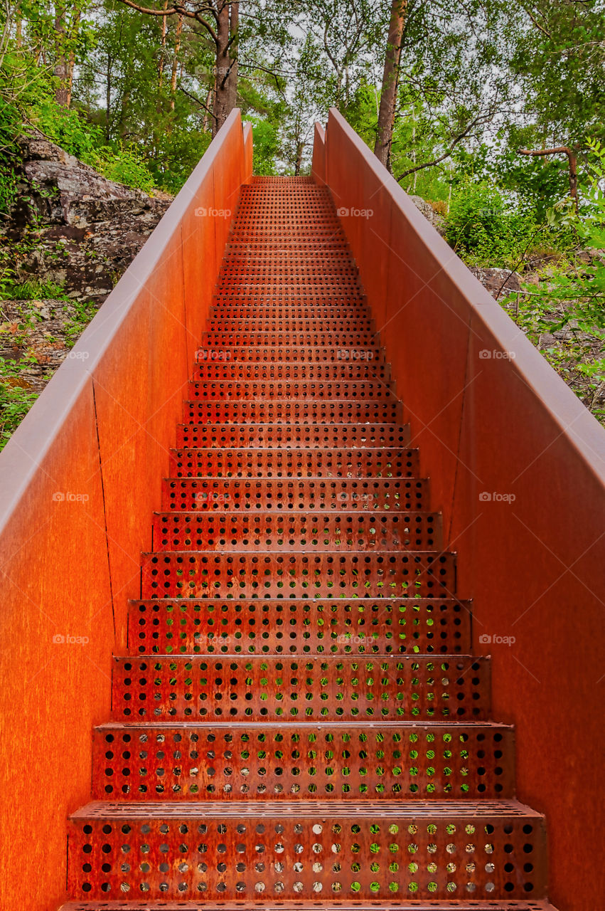 Escape to the Nature. Rusty metal stairs leading up the hill to the forest.