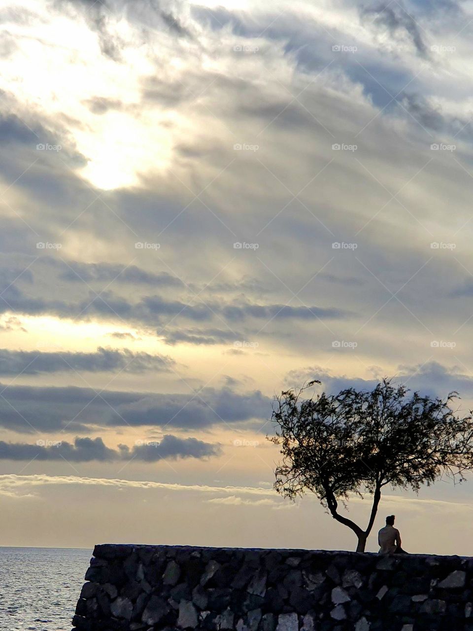 man on a wall dreamily looks at the endless sea