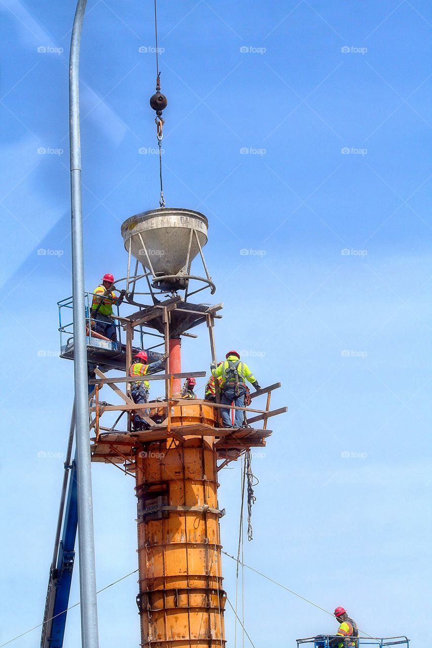 Working Hard. Pouring concrete pillars for a bridge, working high in the air.