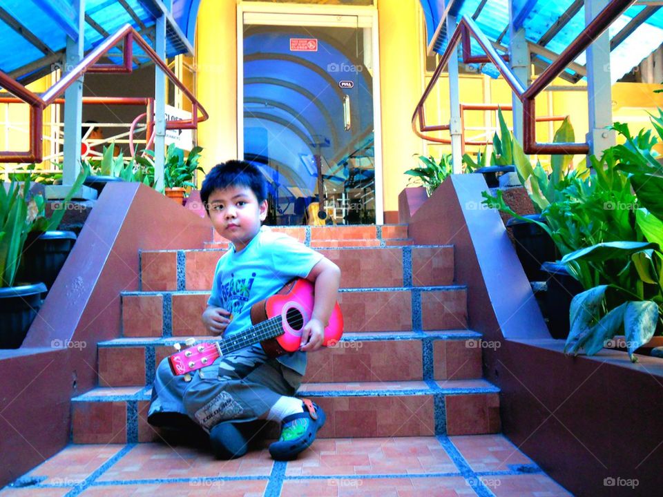 asian child with a yukelele or small guitar