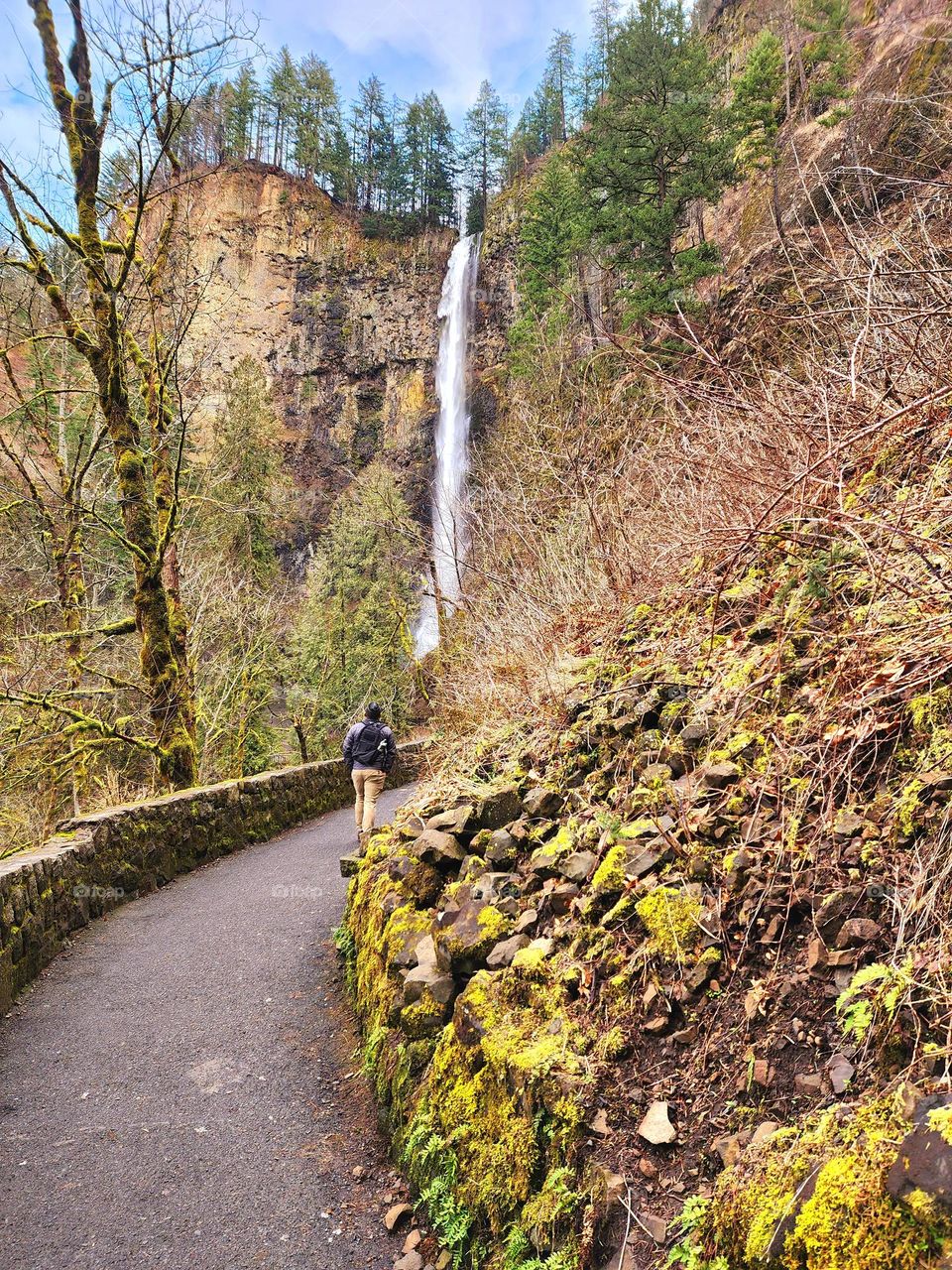 A hiker works his way up a trail to the bridge spanning Multnomah Falls in Oregon
