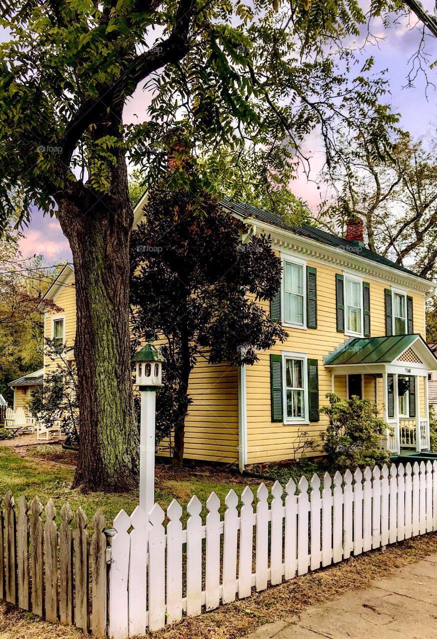 Colonial yellow house with white picket fence 