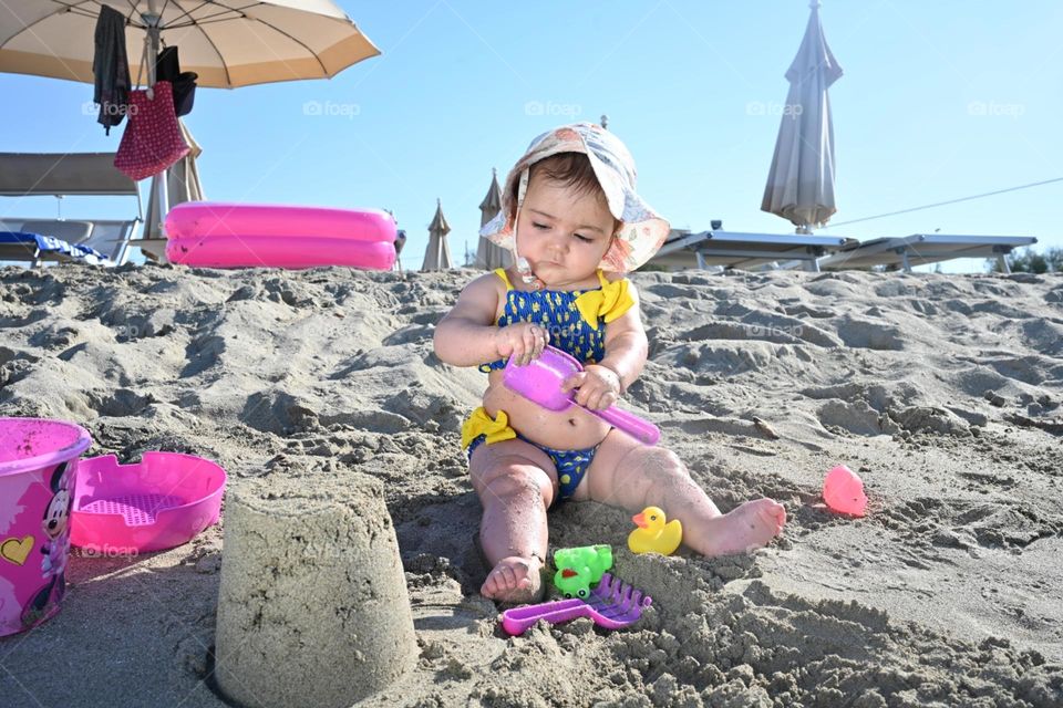 little girl playing with spade and bucket on the beach