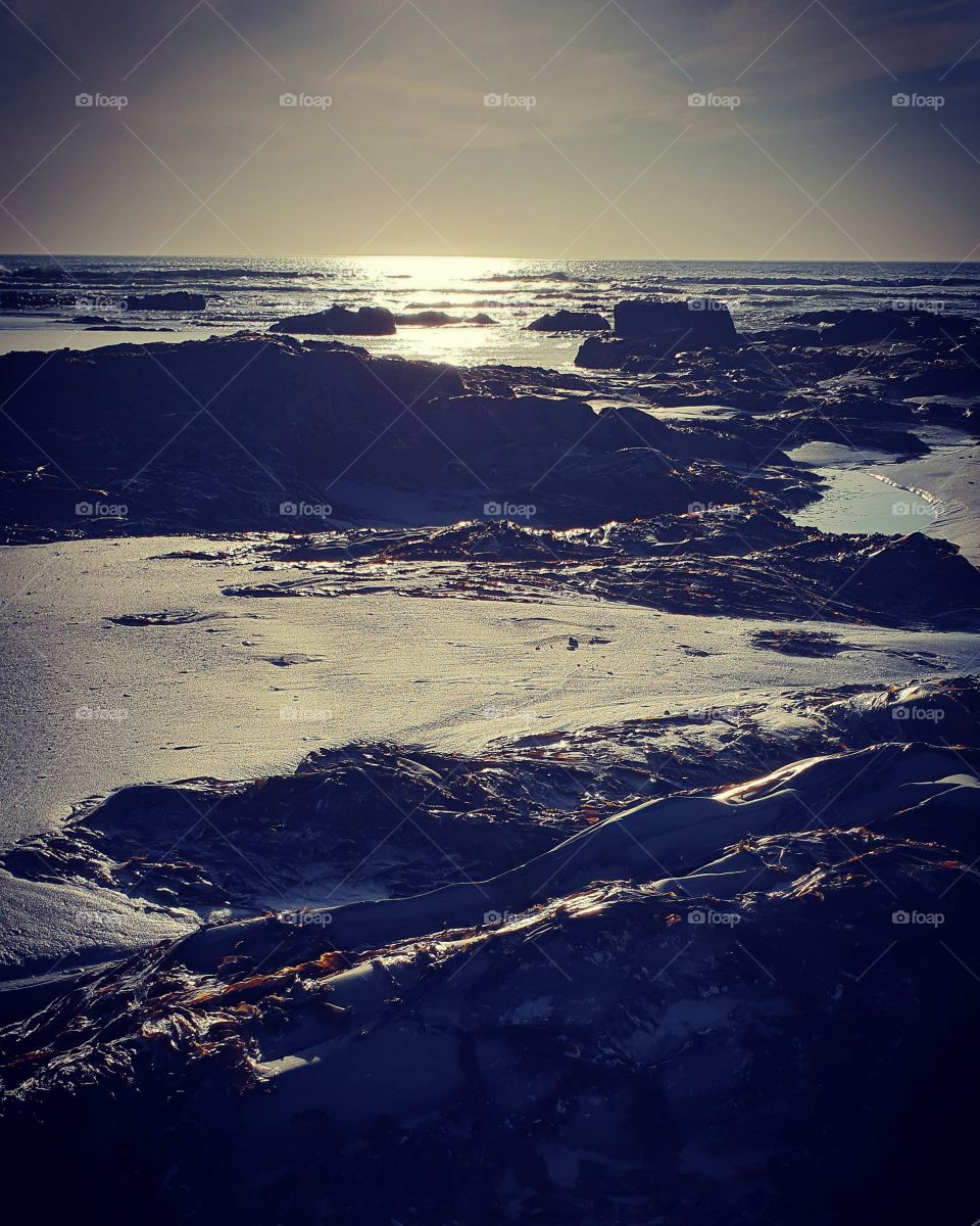 Some sand and rocks and the ocean  creating a beautiful natural masterpiece.