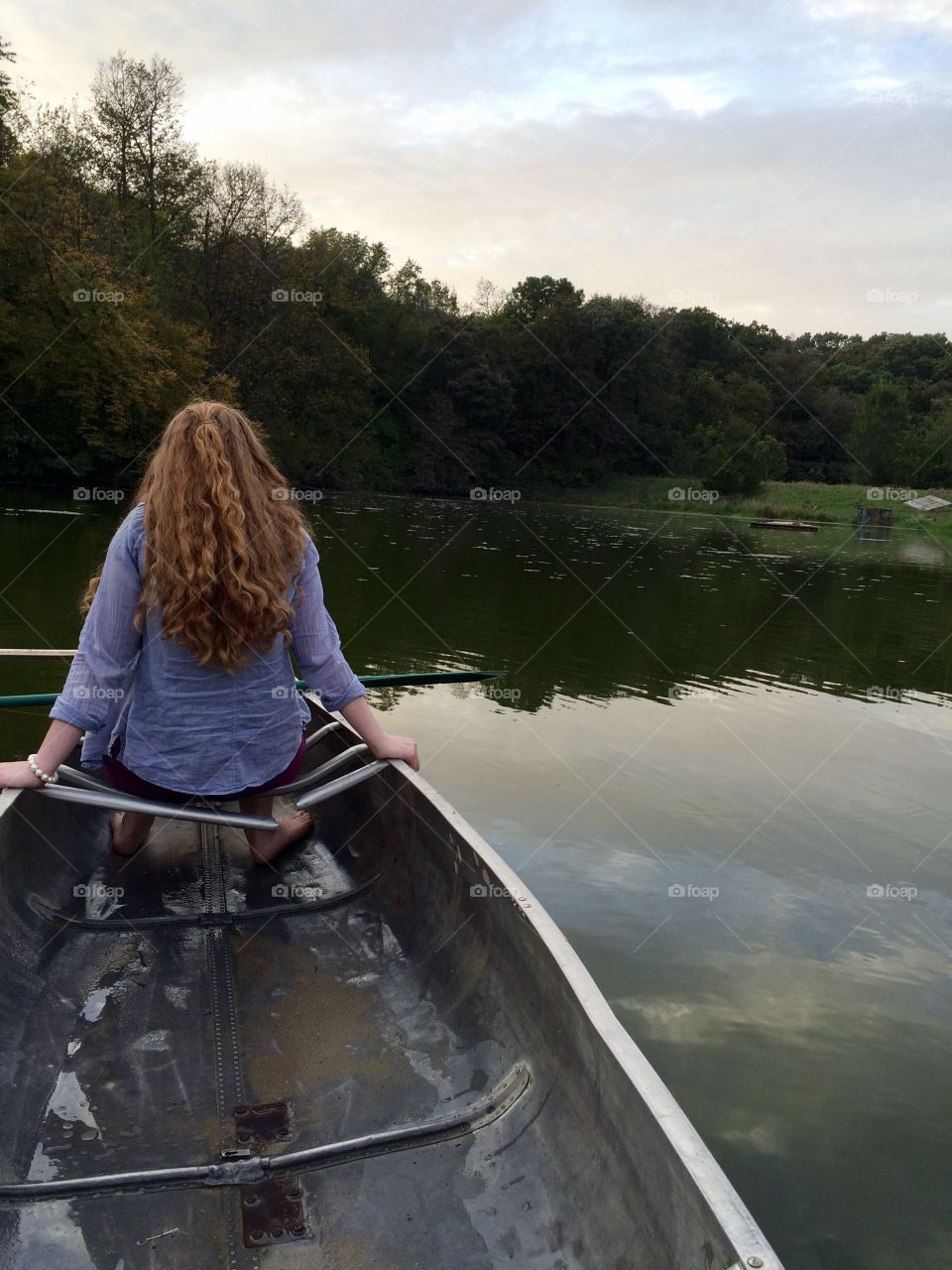 Girl sitting in a canoe floating on a lake surrounded by forest