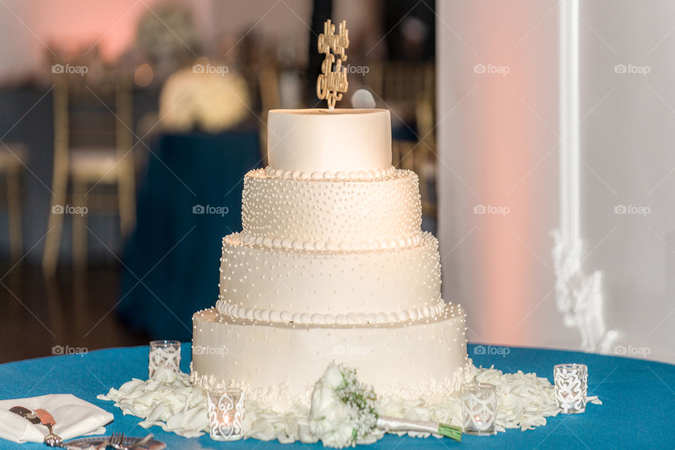 white four tier cake with pink uplighting in background