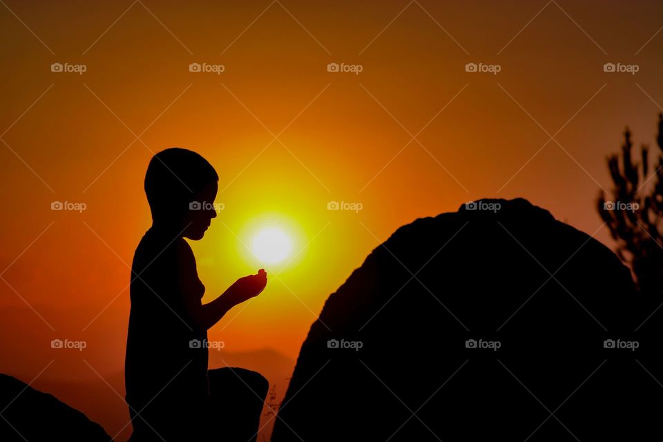 younger boy pray from god in sunset