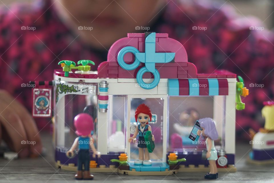 Girl is playing with lego barber shop