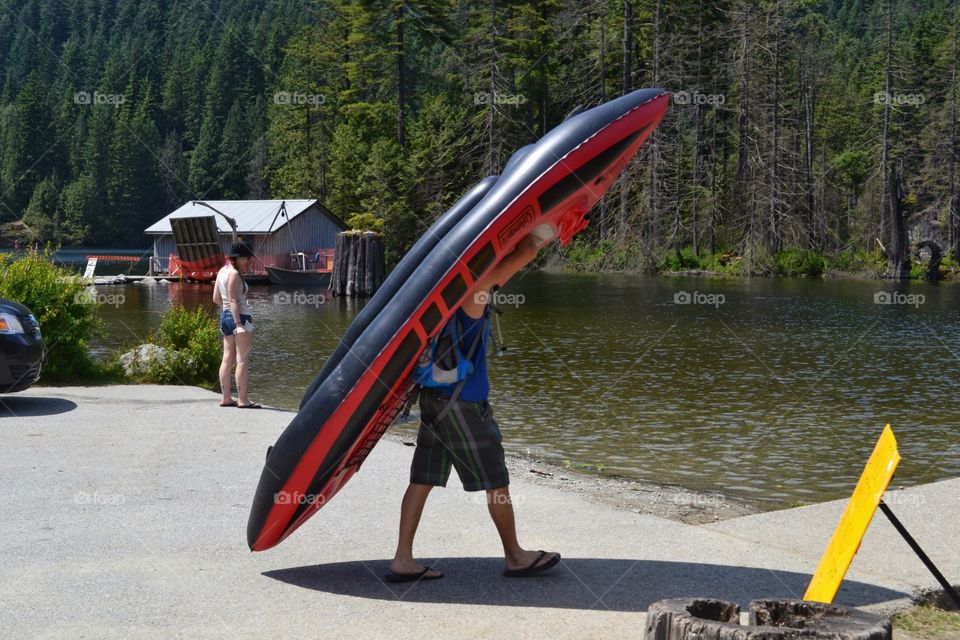 Inflatable kayak. Young person carrying an inflatable kayak to lake