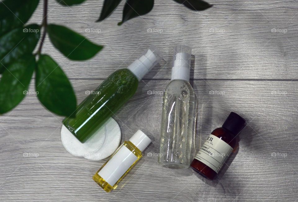 Jars with cream, shampoo and cosmetics on a background with green plants