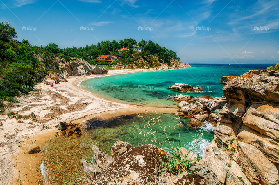 Wild rocky beach with turquoise transparent water in Vourvourou, Halkidiki, Greece