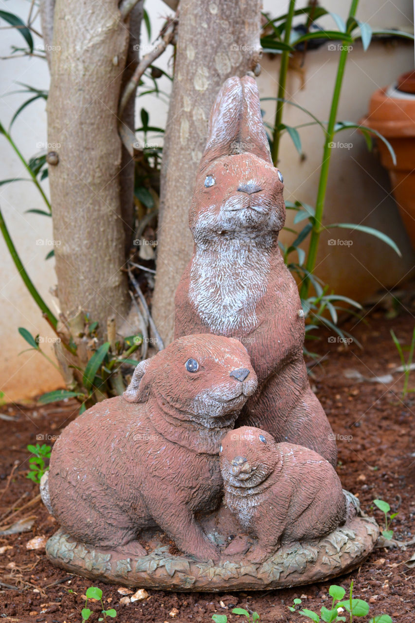 Stucco rabbits family in the garden.