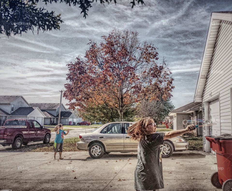 Girl playing with soap bubble in city