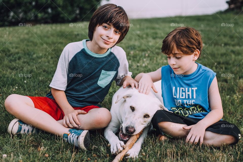 Brothers with their dog sitting in the grass