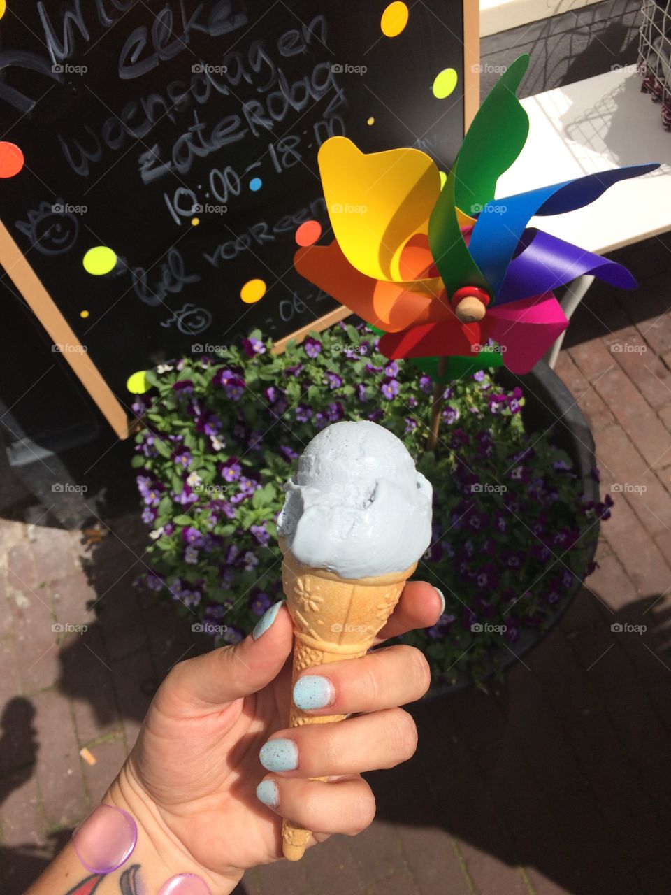 Small blue ice cream in front of plants and pinwheels. 