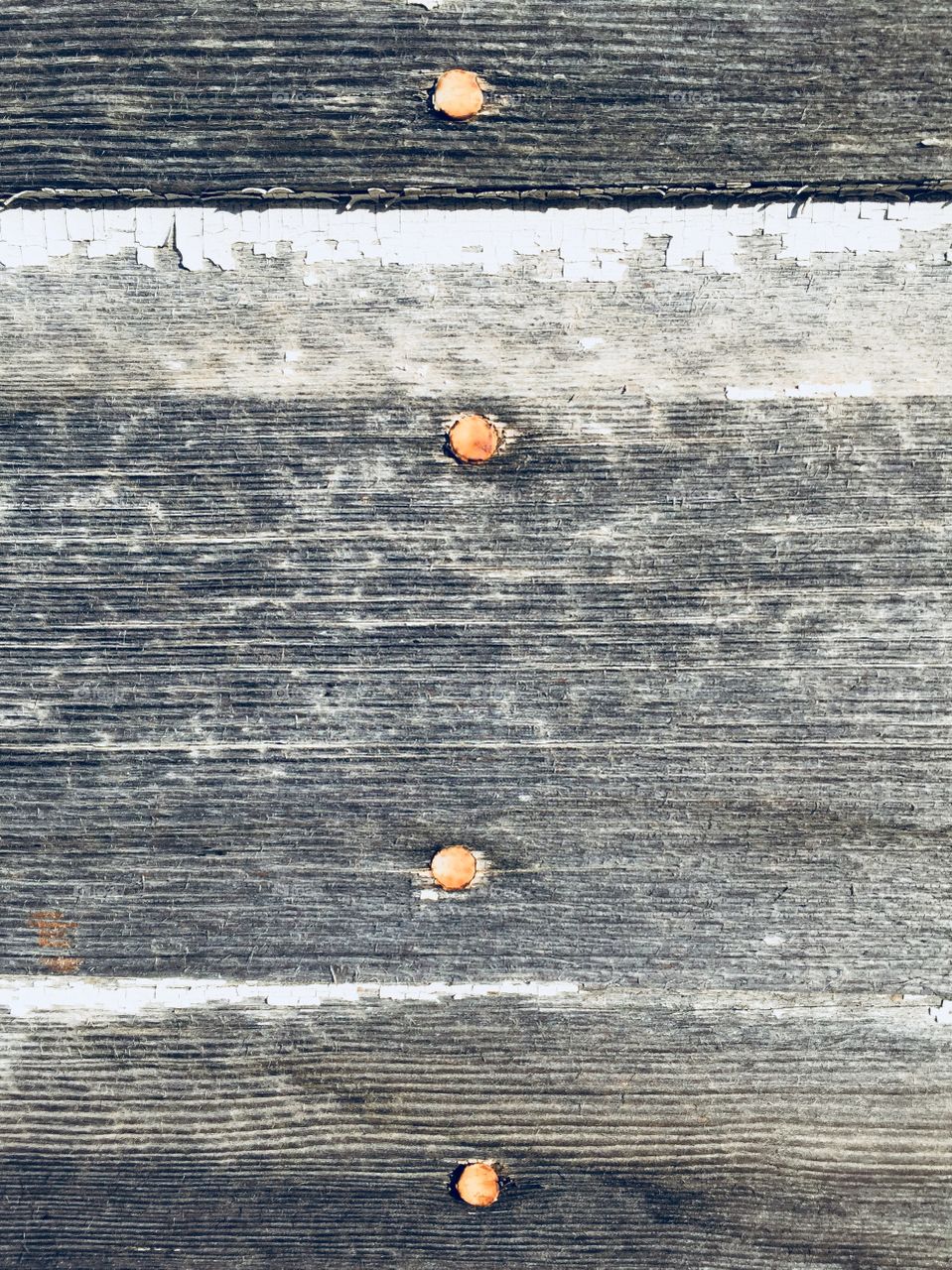 Weathered, textured boards with peeling white paint  and rusty nails 