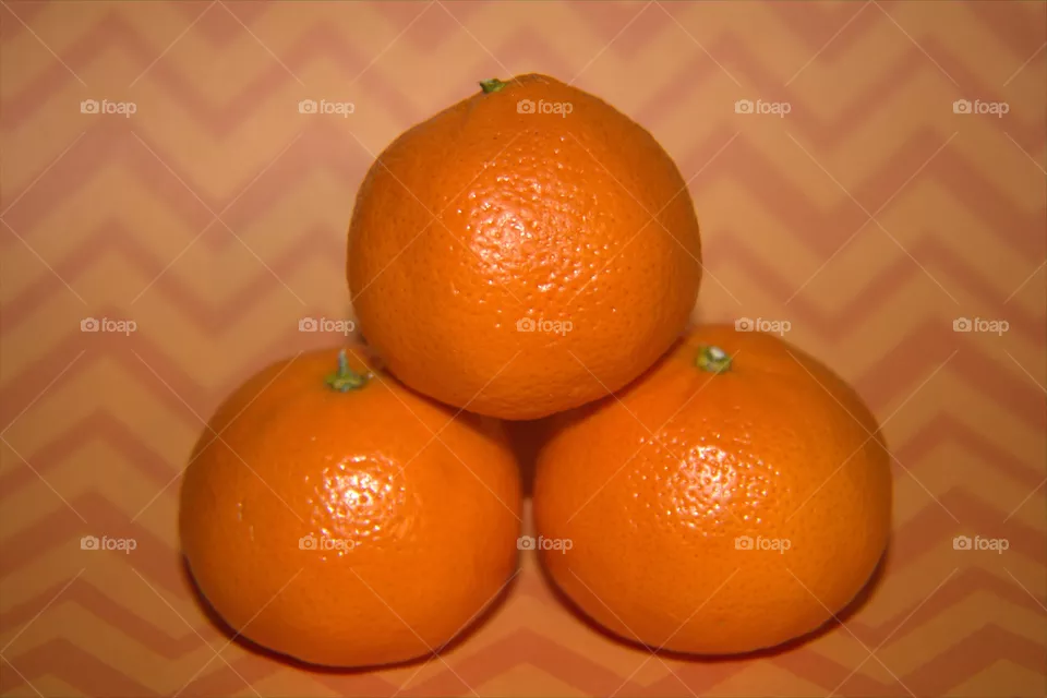 Stacked Oranges in Front of an Orange Abstract Background