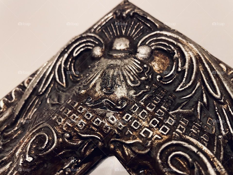 Antique gold coloured ornamentation on mirror frame. Close up and detailed image