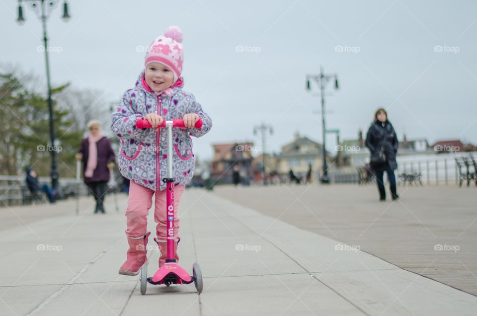 Girl playing riding on push scooter