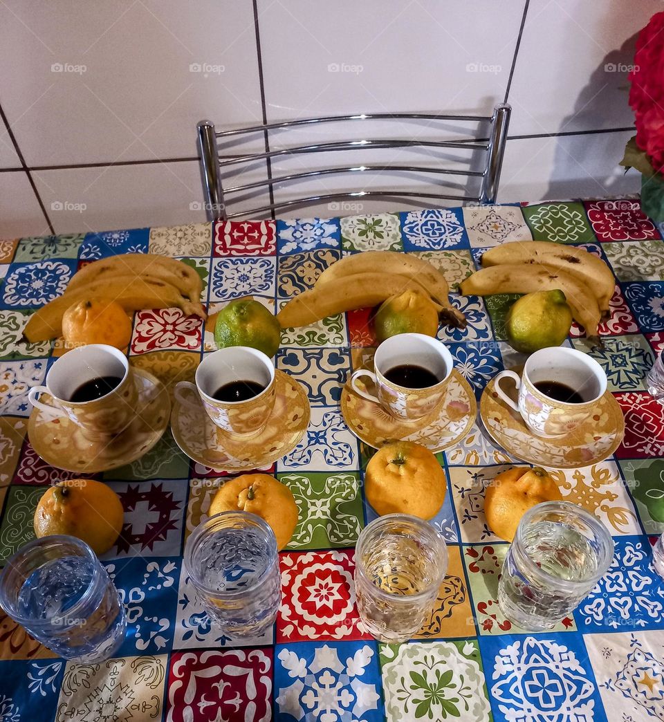 Mesa posta com água, bananas, café e mexericas; para um lanche delicioso e saudável