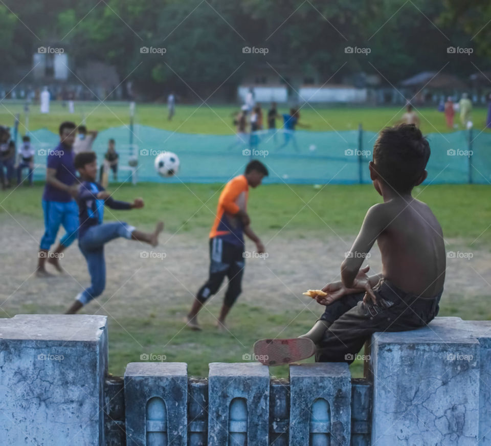 Boy's Playing Football In Playground