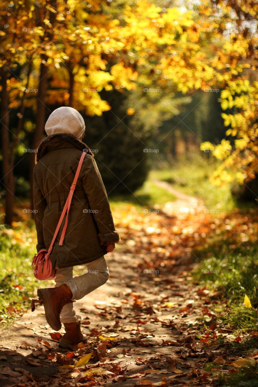 little girl walks in the autumn in the park