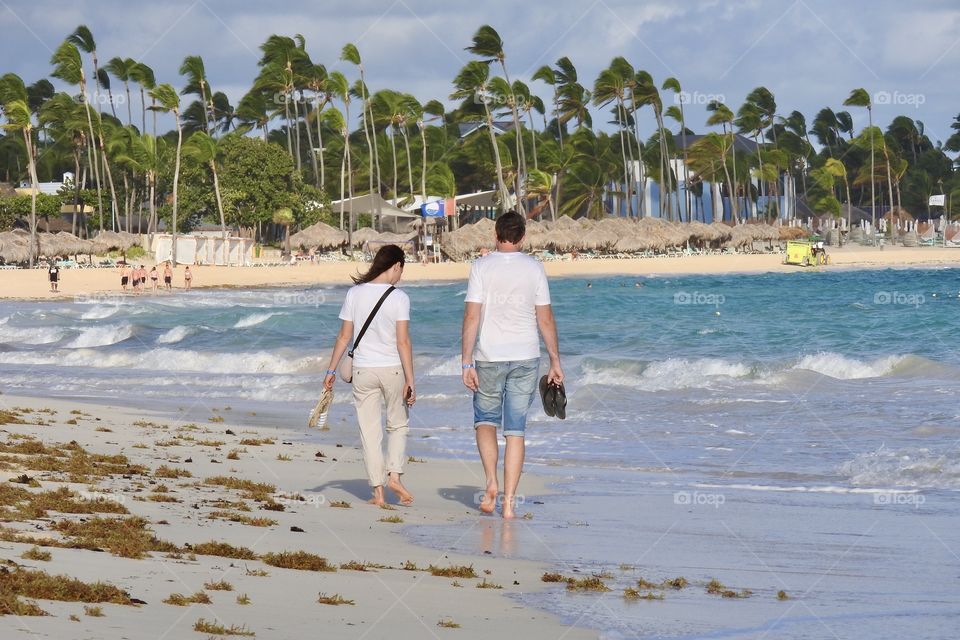 a man and a woman are walking along the ocean