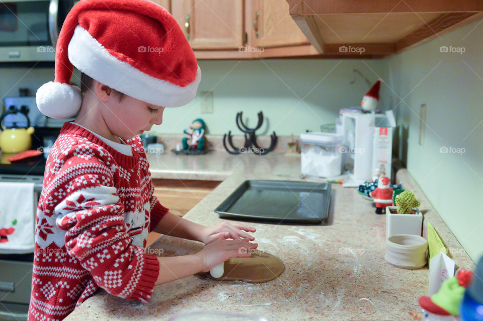 Young boy wearing a Santa hat and making Christmas cookies