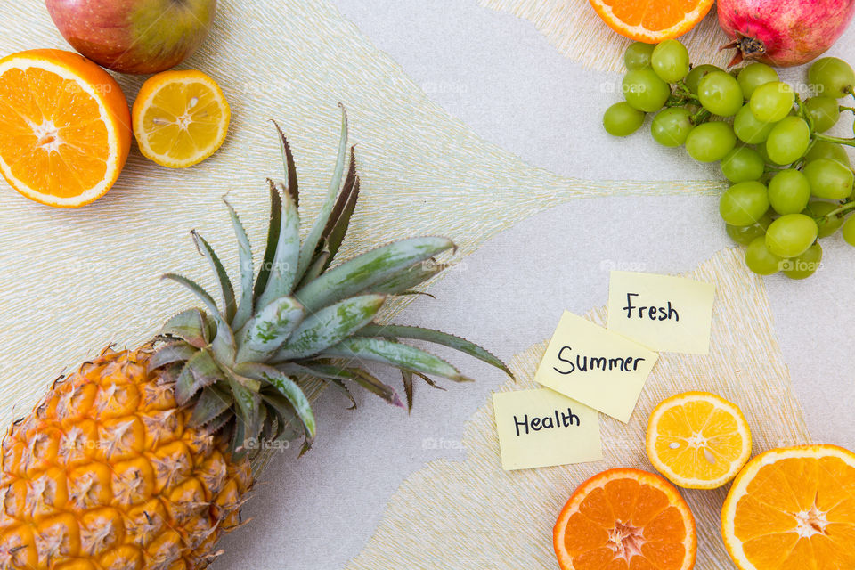 Fresh and healthy fruit to encourage a healthy lifestyle. Handwritten sticky notes with words fresh summer health on it. Flat lay with textured background with variety of fresh fruit.