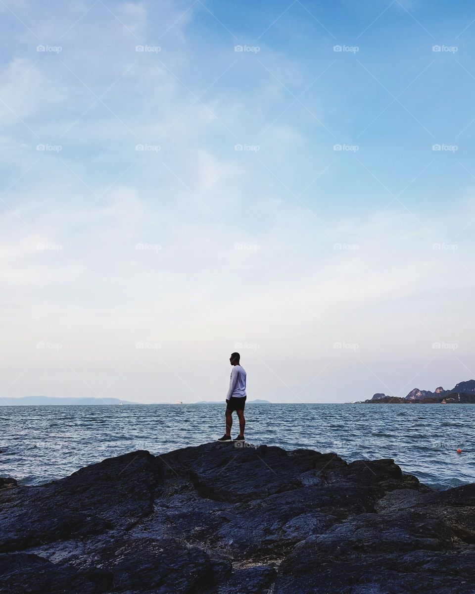 Man standing on stone at seashore