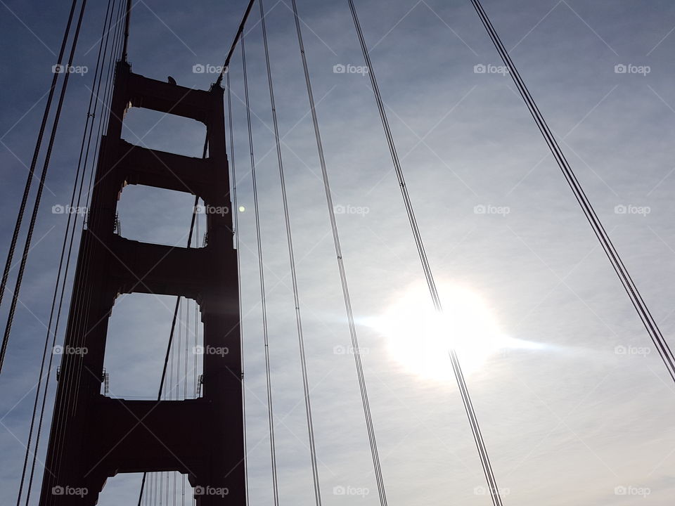 view of bright sun beaming through clouds and silhouette of the Golden Gate Bridge in San Francisco, America