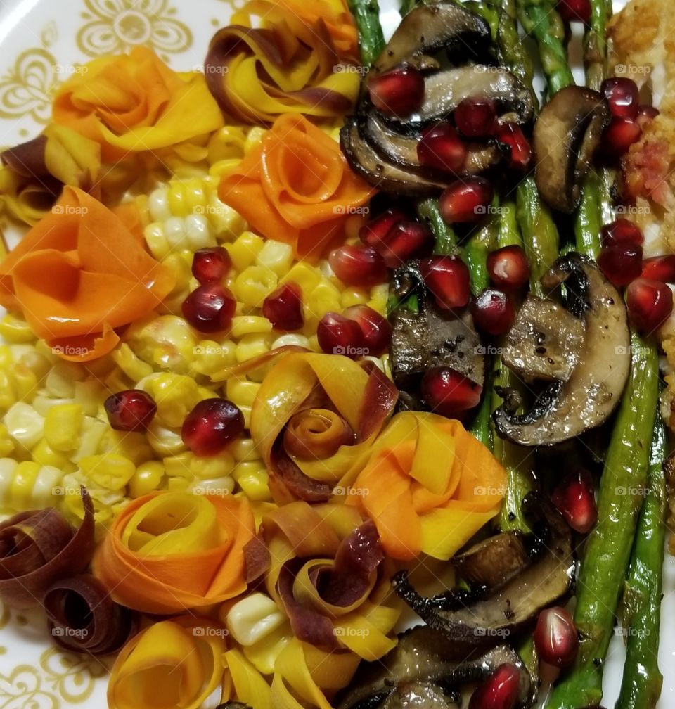 An Autumn harvest celebration of colors, flavors, and textures. Asparagus, mushrooms, and bi-color corn. Multi color carrot strip were steamed, then fashioned into flowers to celebrate the harvest. Finished with a sprinkling of  pomegranate arils.