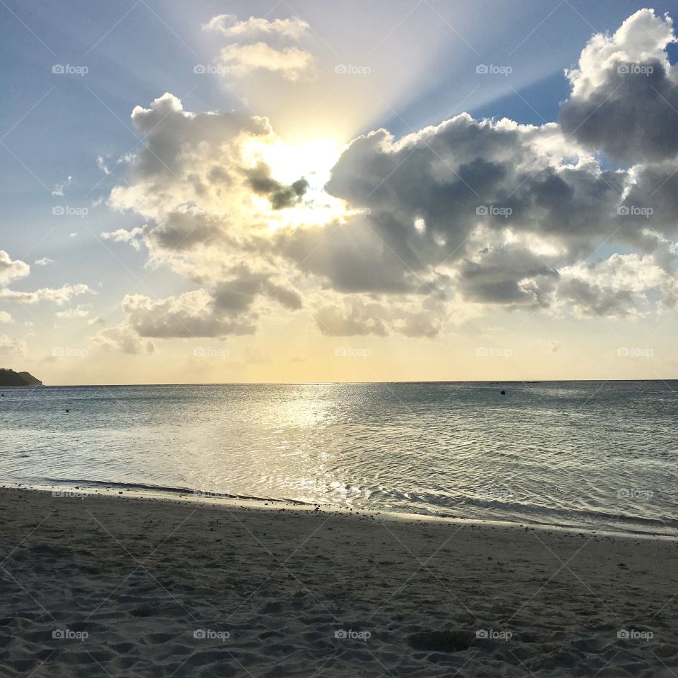 The sun shined through clouds on a gorgeous beach in Guam.