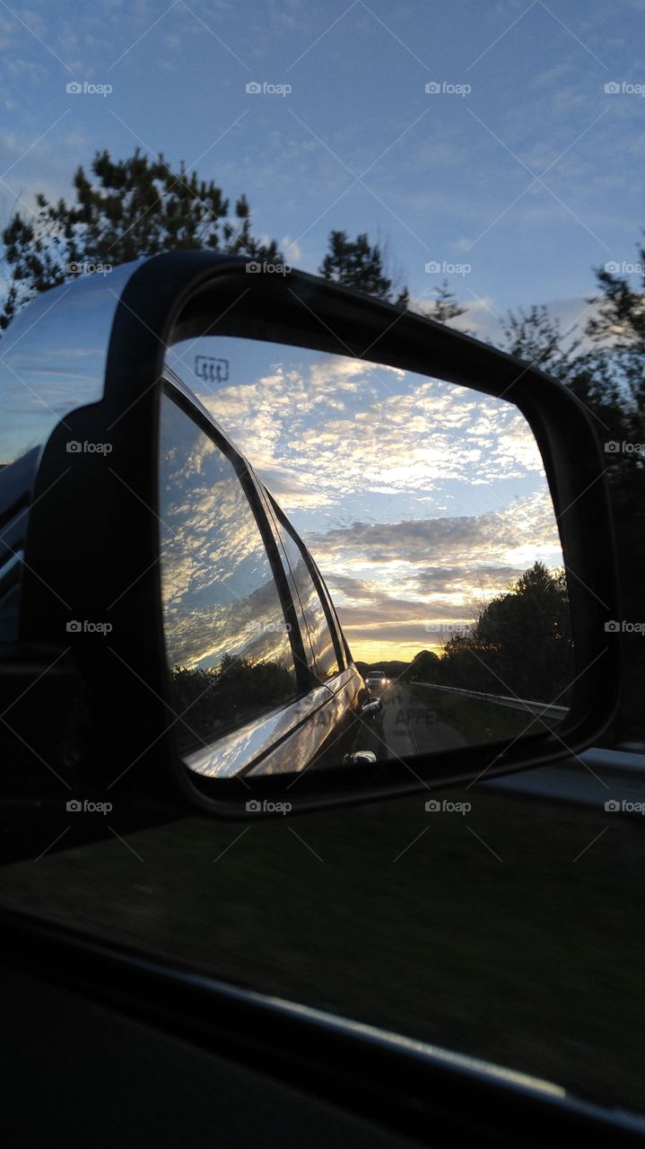 the sunset captured in the rear view mirror and reflecting of off the car from the passenger seat