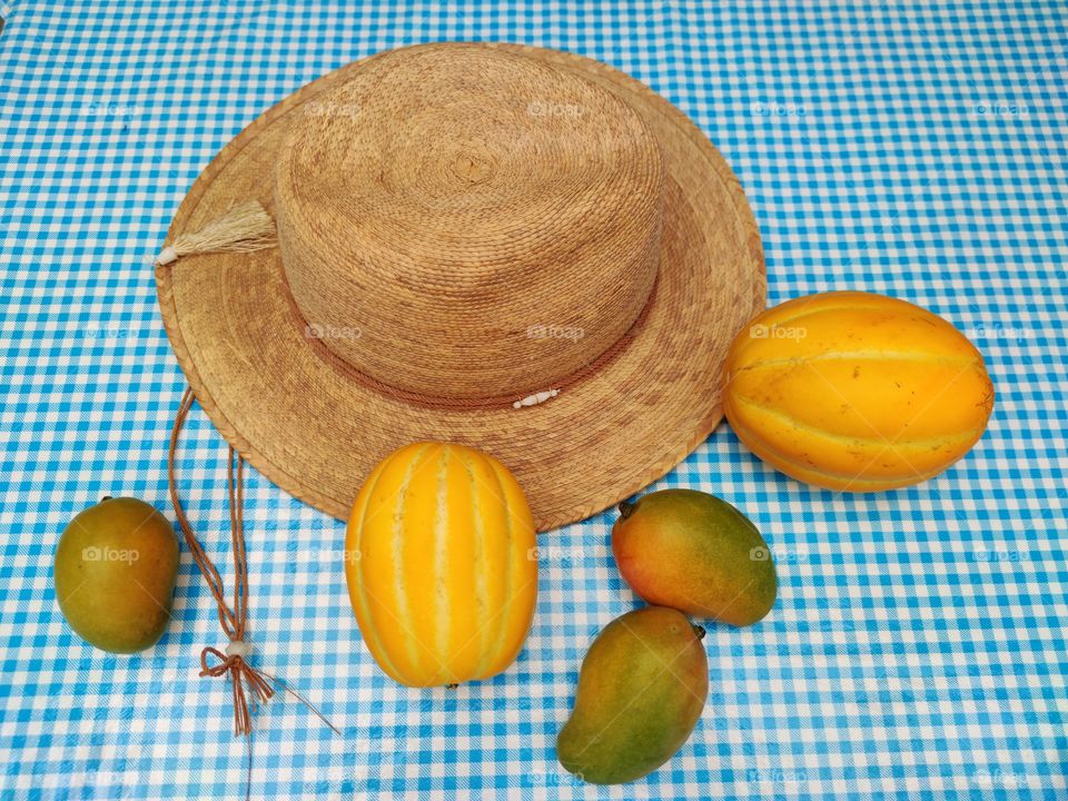 A Chinese melon, mangoes and a straw hat