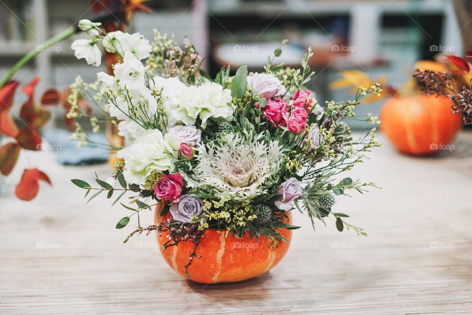 DIY autumn flower arrangement bouquet in pumpkin, florist at work, floristry studio