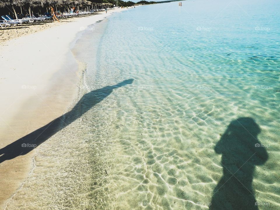 Couple at the beach - shadows on clear turquoise waters of the ocean
