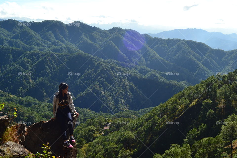 One woman sitting in a cliff over the mountains