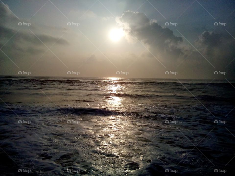 This is a beautiful sunrise at BesantNagar beach in Chennai. Beautiful water from the sea. The reflection of the sunrise is gold on these water. Nothing is relaxing when the waves touch the feet. The clouds add a beautiful effect.