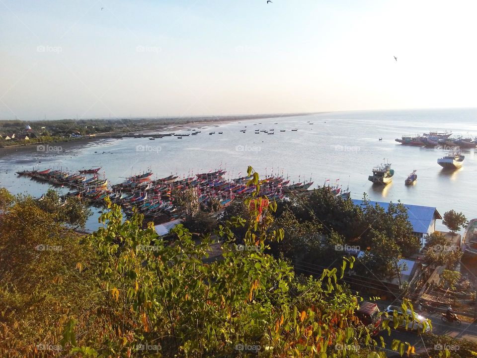 Sunset view on the beach with many fishing boats leaning, photo taken from the top of the hill