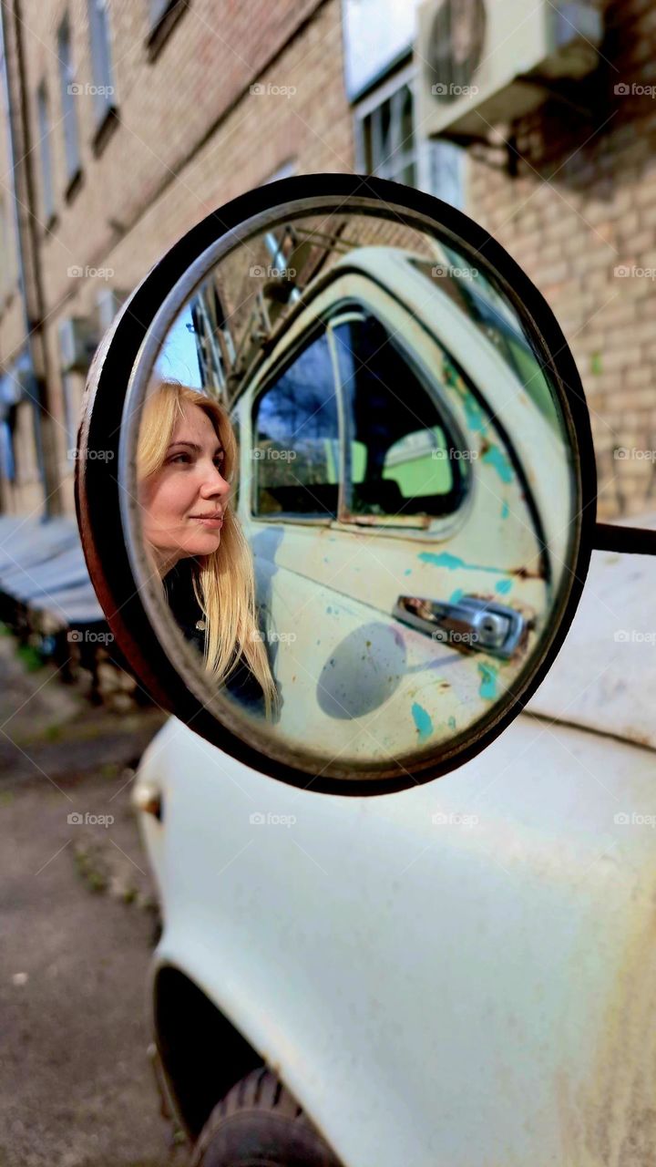 girl looking in the mirror of a retro car
