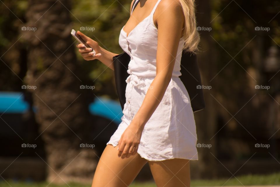 Blond woman walking with her phone in her hand